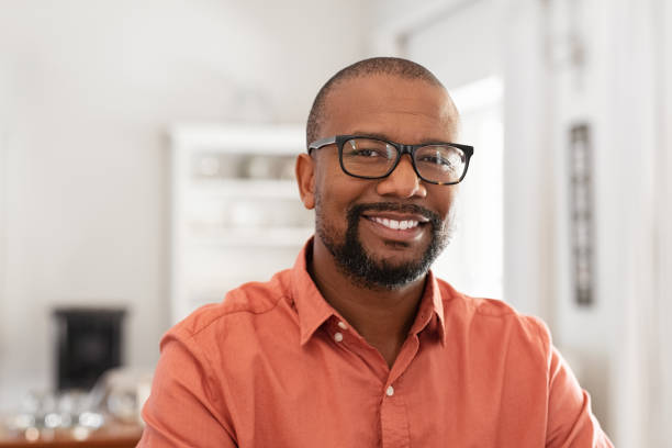 Smiling mature man wearing spectacles looking at camera. Portrait of black confident man at home. Successful entrepreneur feeling satisfied.