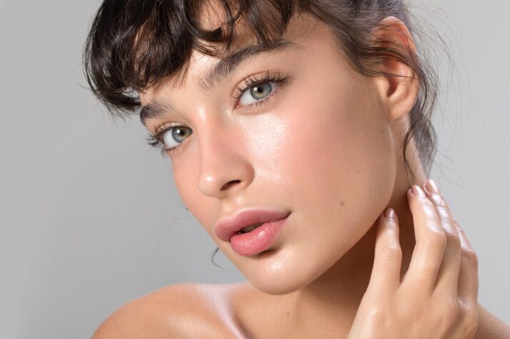 Close up studio shot of a beautiful woman with perfect skin, she touching her face