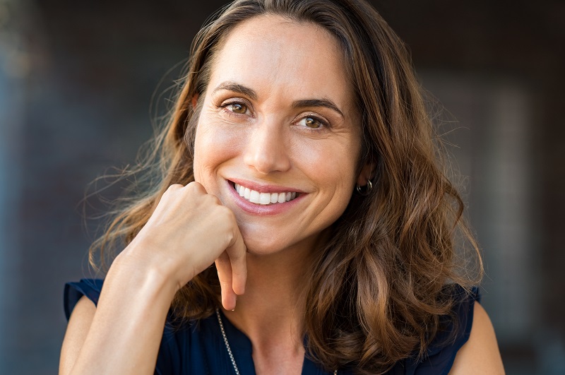 Portrait of a happy smiling mature woman with hand on chin looking at camera. 